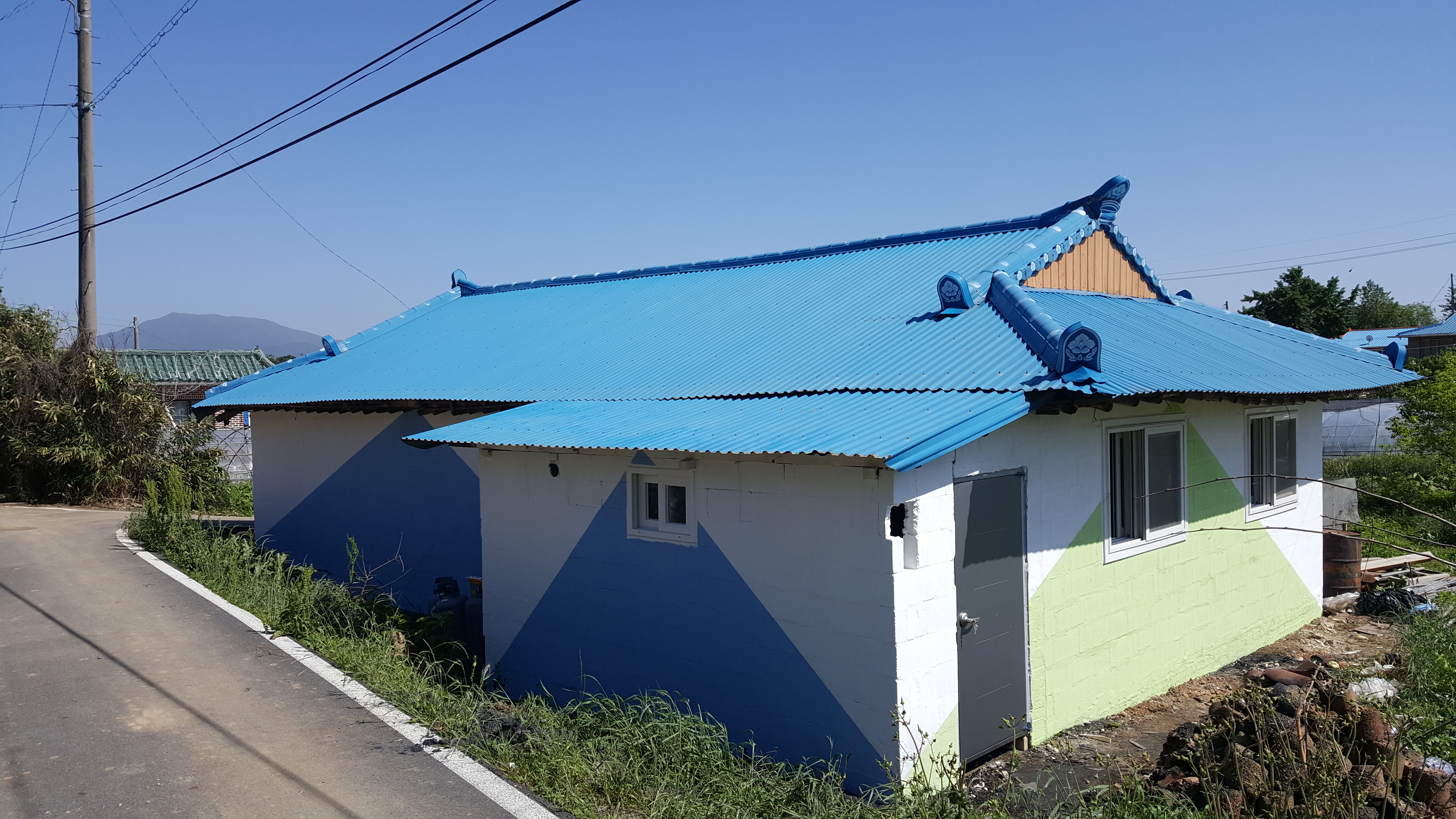 페인트칠을 새로하여 깨끗하고 훤해진 집의 파란색 지붕과 건물 벽의 모습